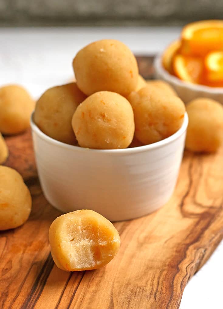 a bowl of paleo vegan orange creamsicle bites with one in front of the bowl with a bite taken out 