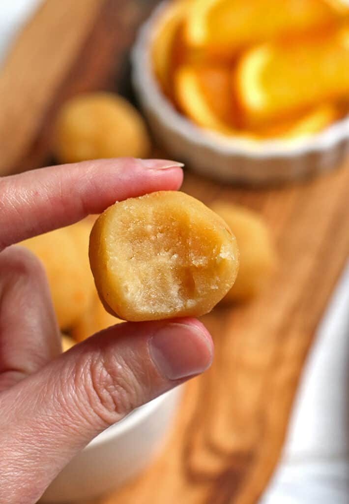 hand holding a paleo orange creamsicle bite with a bite taken out of it 