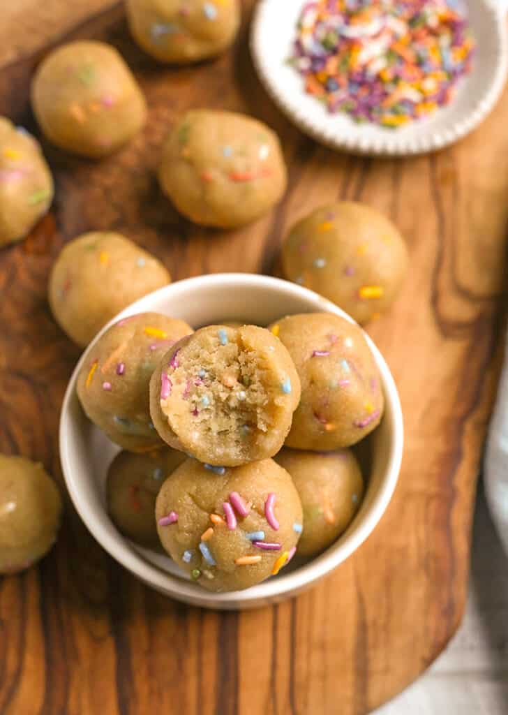 a bowl of birthday cake bites with a bite taken out of the top one 