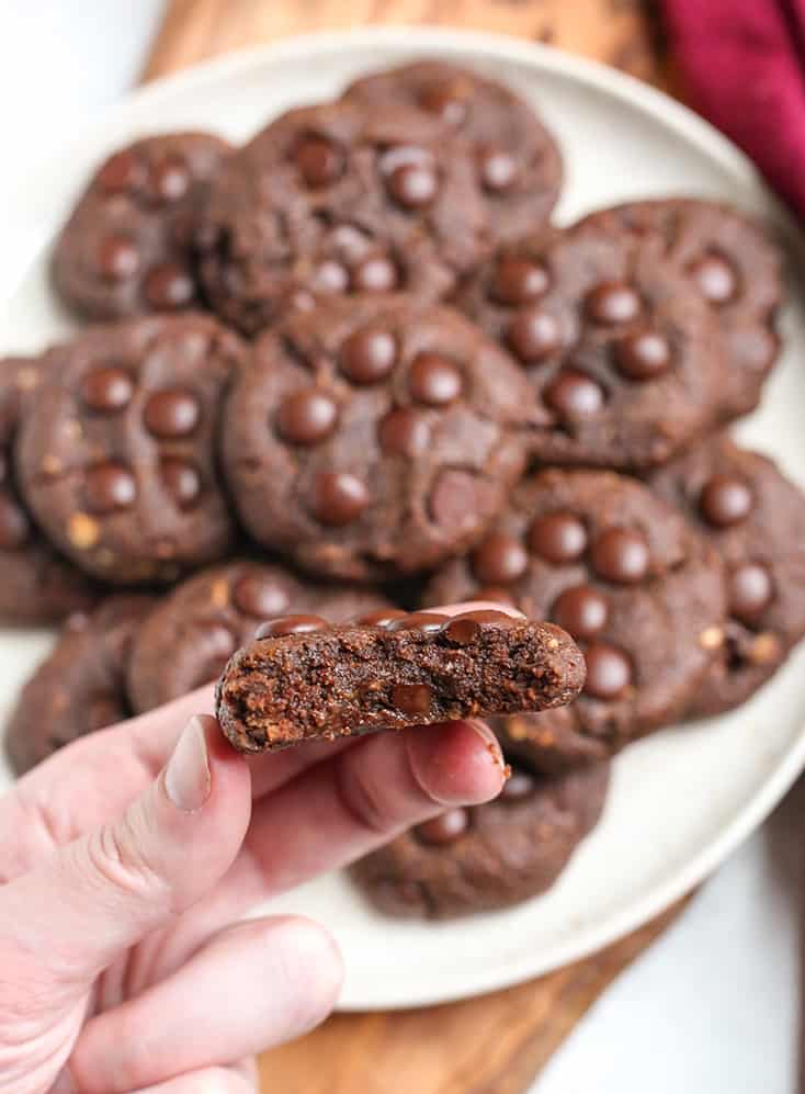 a hand holding a paleo vegan pumpkin chocolate cookie with a bite taken out 