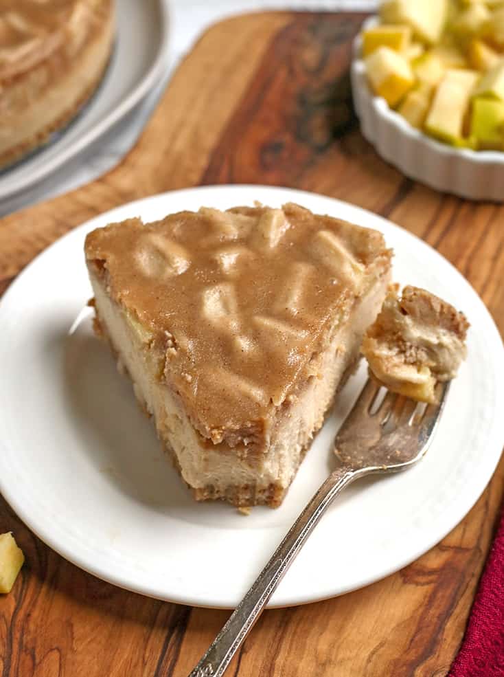 a piece of vegan paleo caramel apple cheesecake on a plate with a bite taken out 