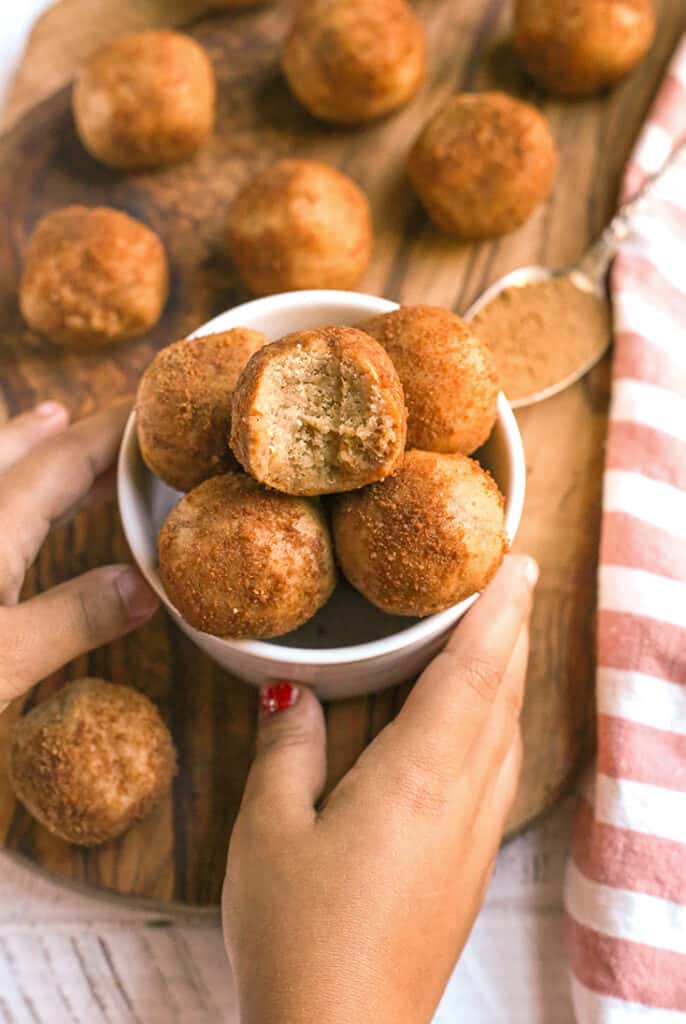 small hands holding a bowl of paleo cinnamon roll bites 