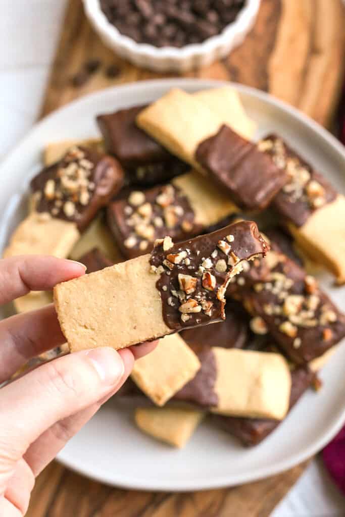 a hand holding a shortbread cookie with a bite taken out