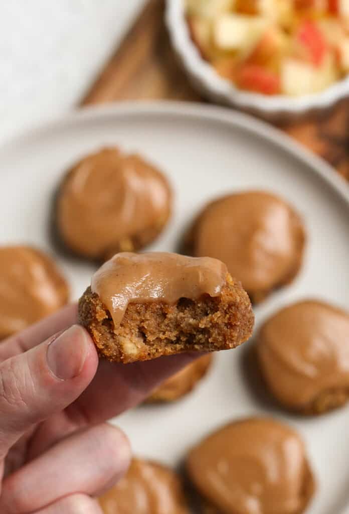 hand holding a paleo apple cookie with glaze with a bite taken out