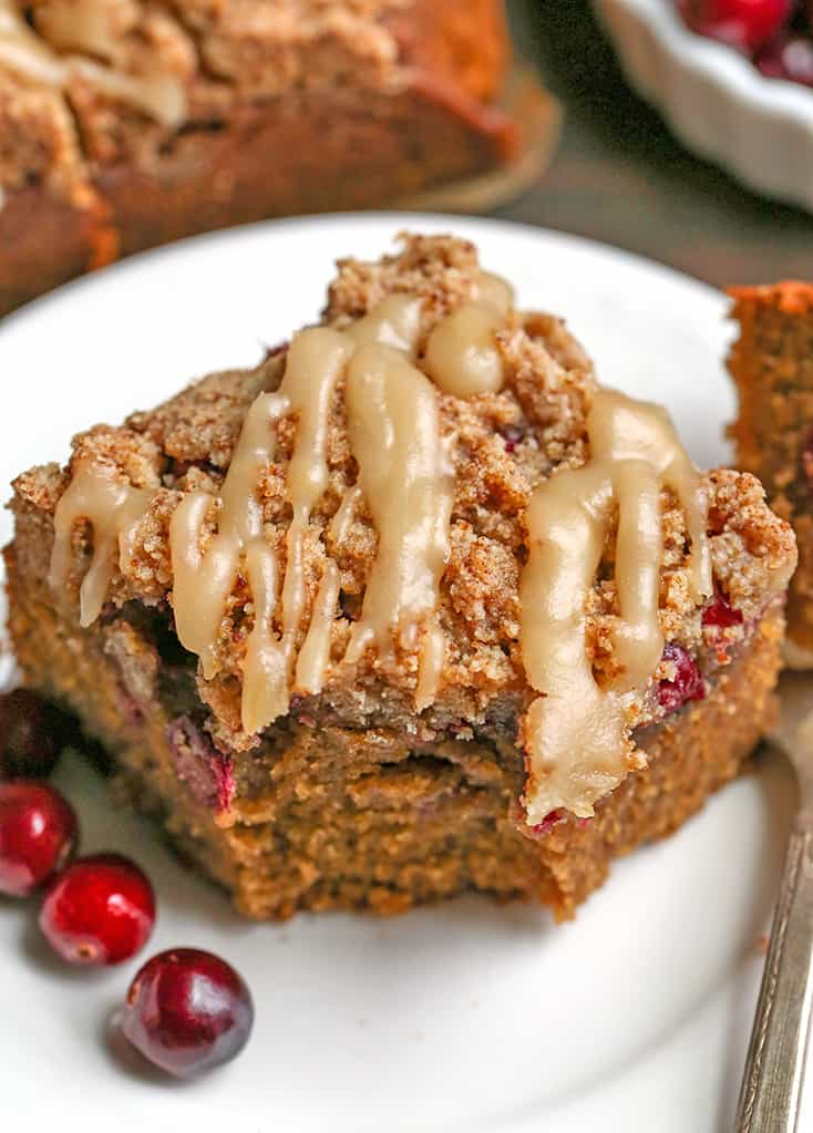 a close up shot of a piece of paleo cranberry coffee cake with a bite taken out 