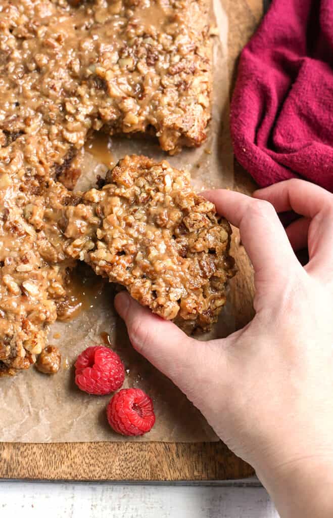 a hand holding a paleo pecan sticky bun