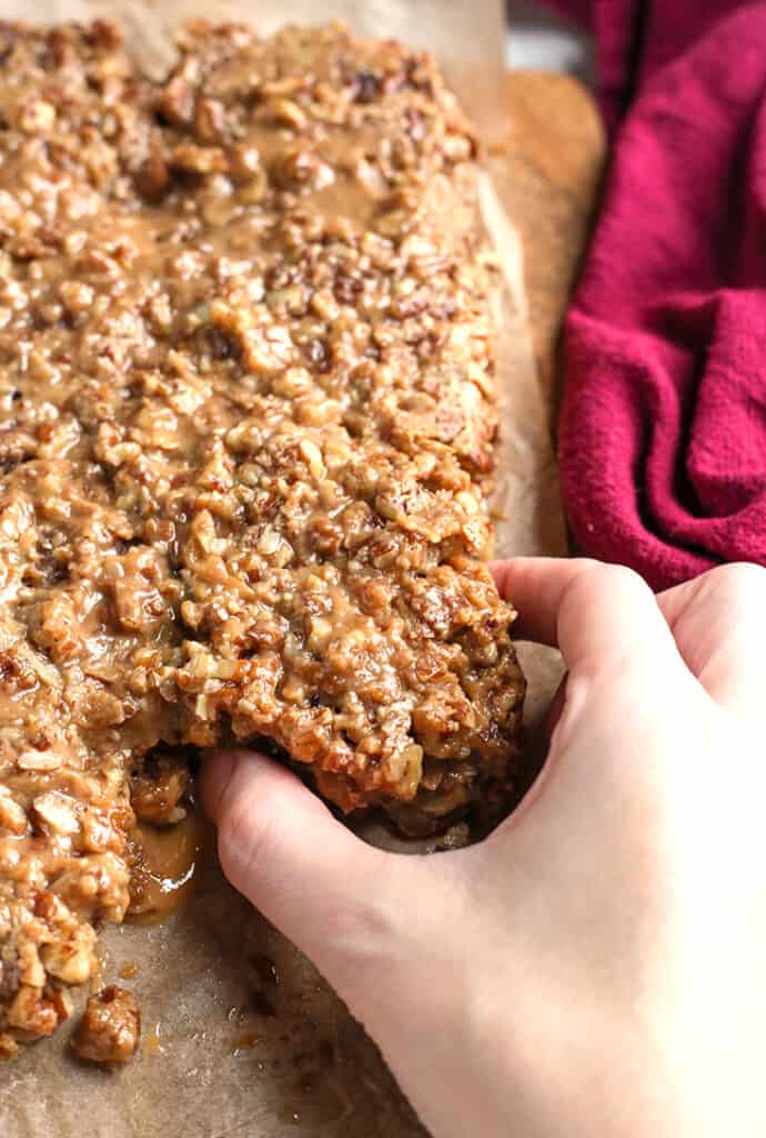 a hand pulling a pecan sticky bun away from the others