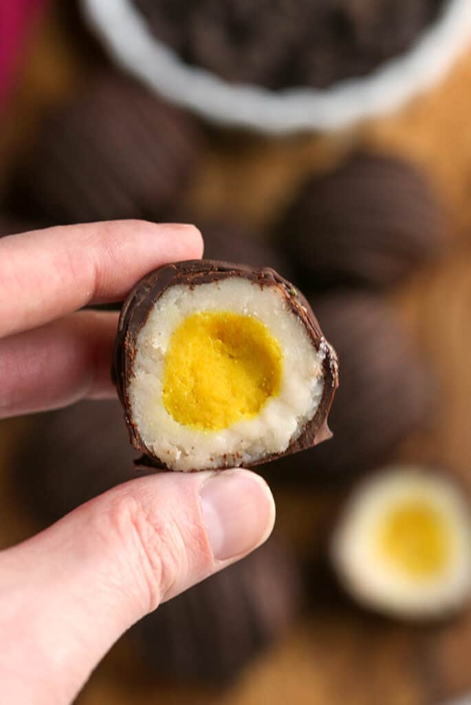 a hand holding a vegan paleo cadbury creme egg, the middle showing 