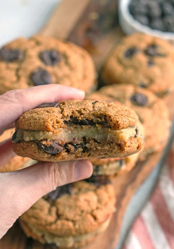 hand holding a paleo chocolate chip cookie dough sandwich with a bite taken out 