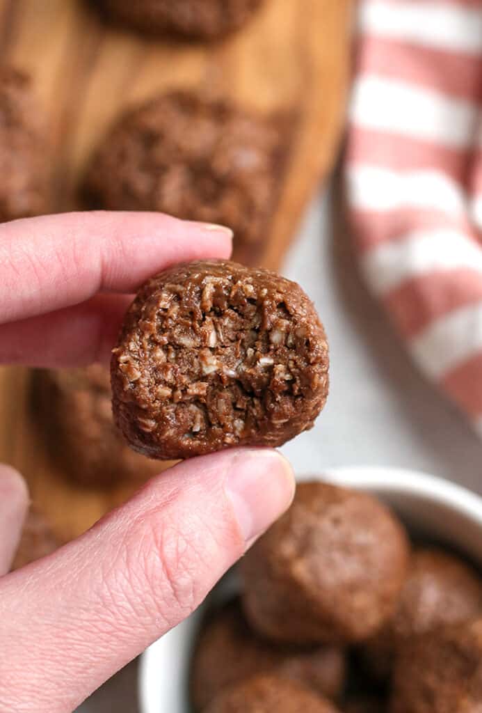 a hand holding a paleo chocolate coconut bite with a bite taken out 