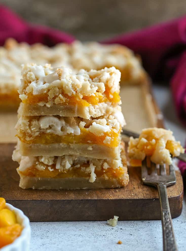 paleo vegan mango crumb bars in a stack with a bite taken out of the top one