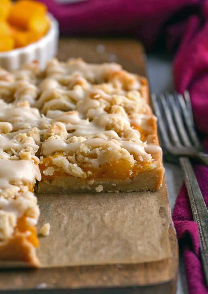 paleo vegan mango crumb bars on a cutting board, one removed so the inside is showing 