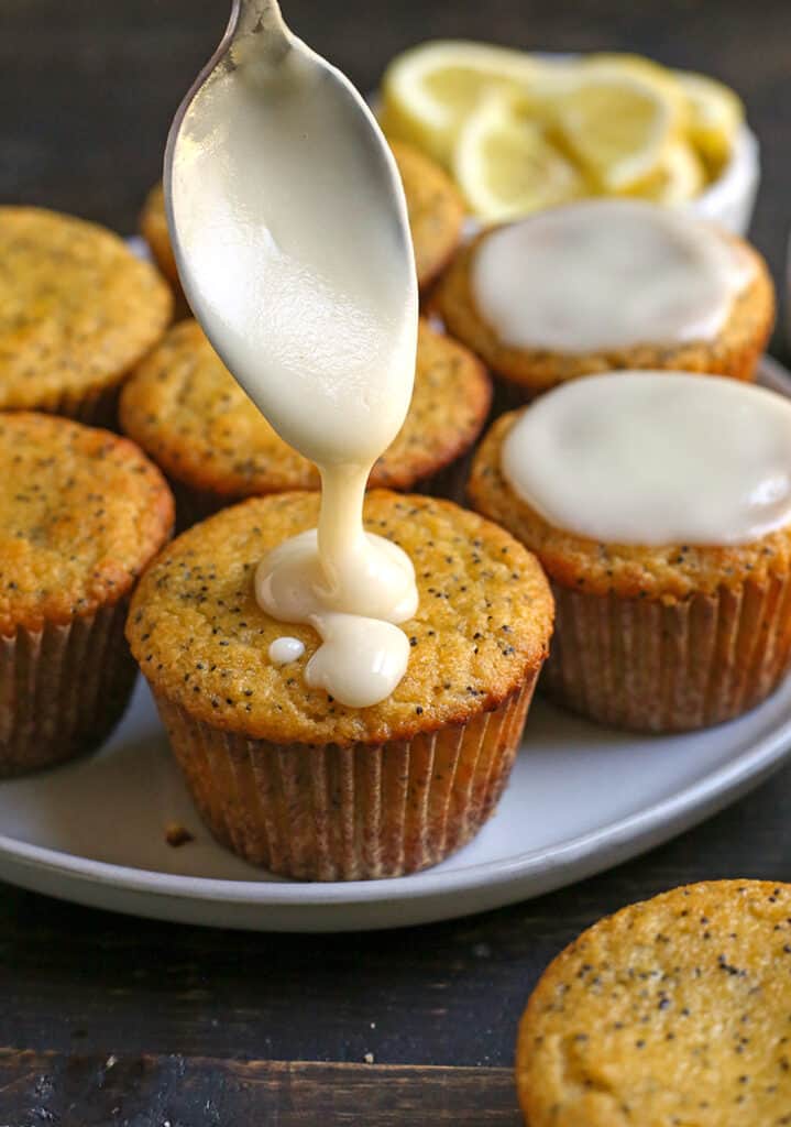 glaze being drizzled on a lemon poppy seed muffin 