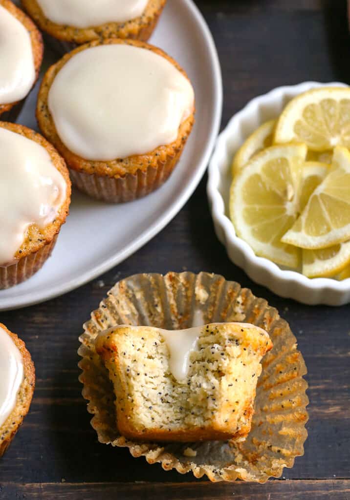 a bite taken out of a lemon poppy seed muffin, whole muffins in the background