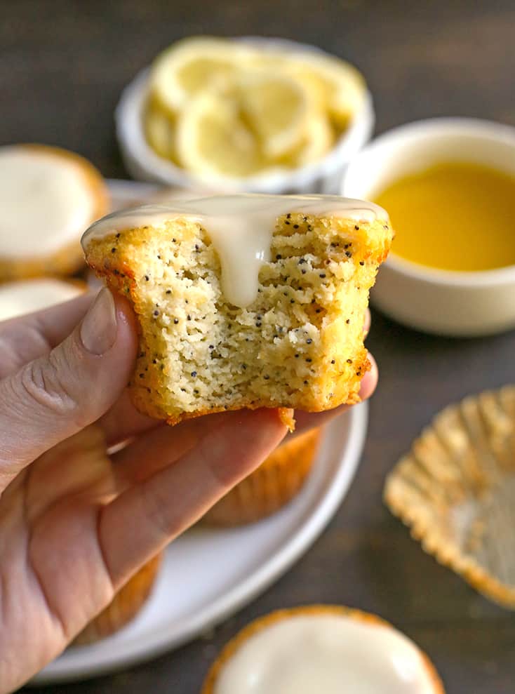 a hand holding a lemon poppy seed muffin 