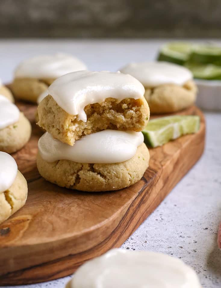 a stack of paleo lime cookies on a cutting board, a bite taken out of one 