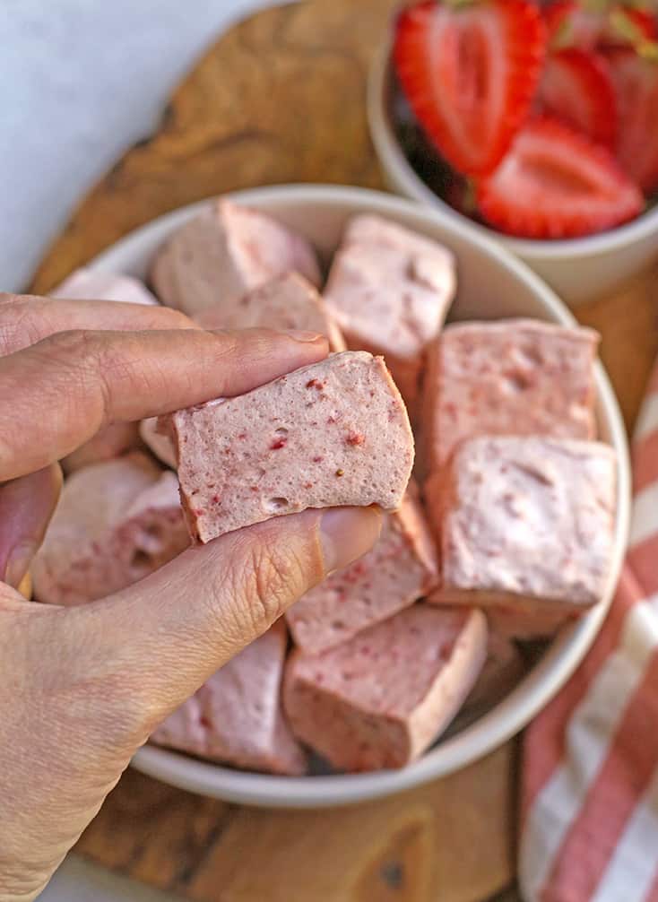 a hand holding a paleo strawberry marshmallows 