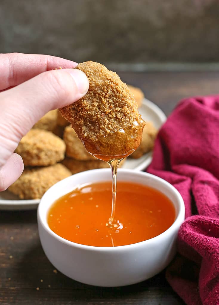 paleo chicken nuggets dipping in honey with a drizzle 