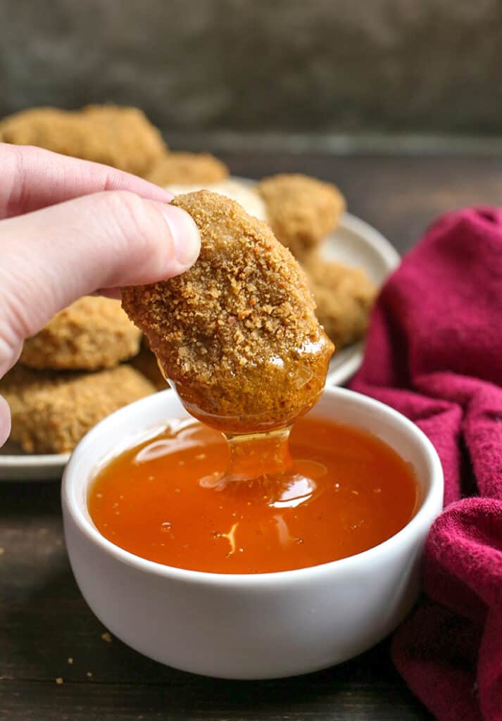 paleo chicken nugget dipping in a bowl of honey