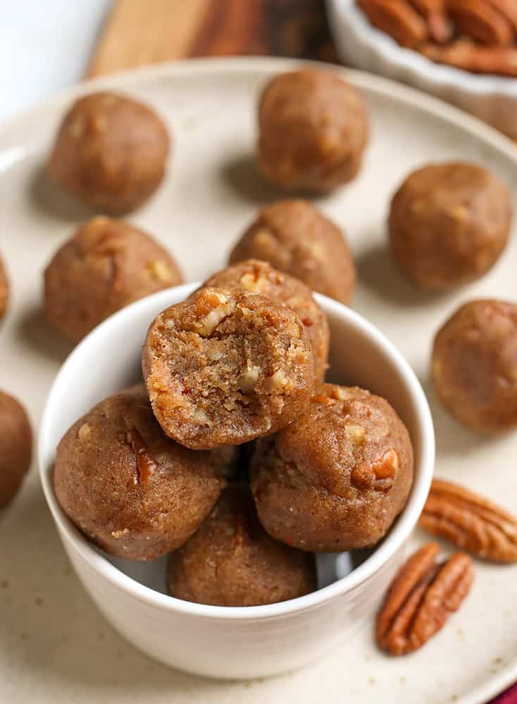 bowl of vegan paleo pecan pie bites with one having a bite taken out of it 