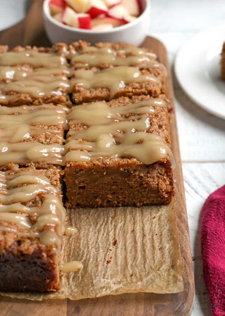 a cutting board with paleo apple crisp coffee cake on it, one piece removed 