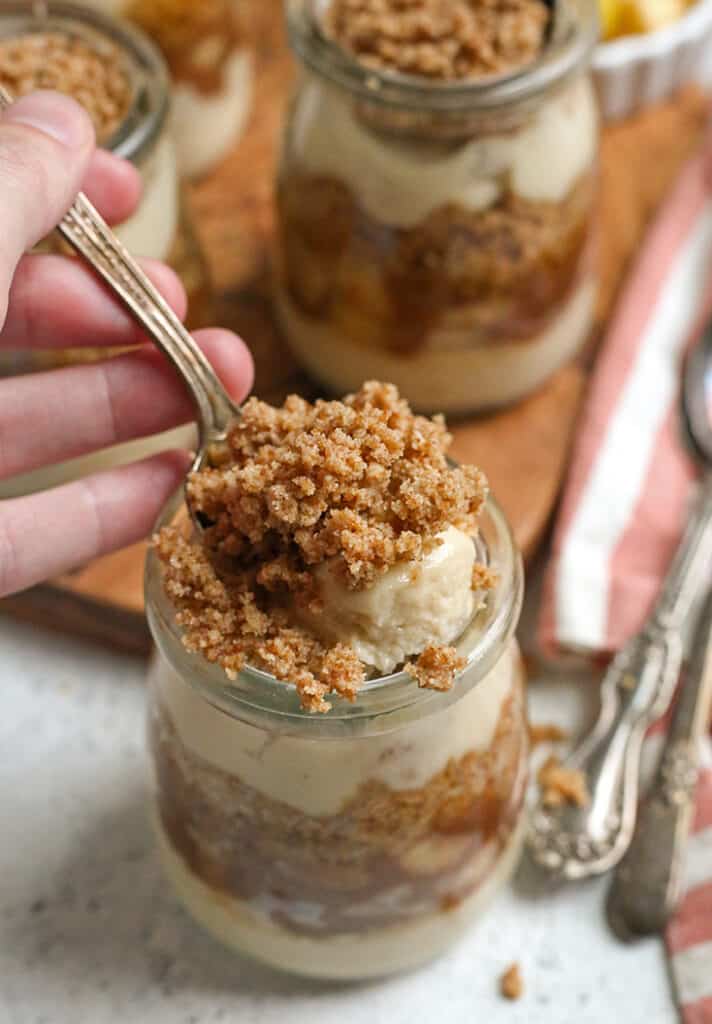 a hand taking a scoop out of a paleo vegan caramel apple parfait
