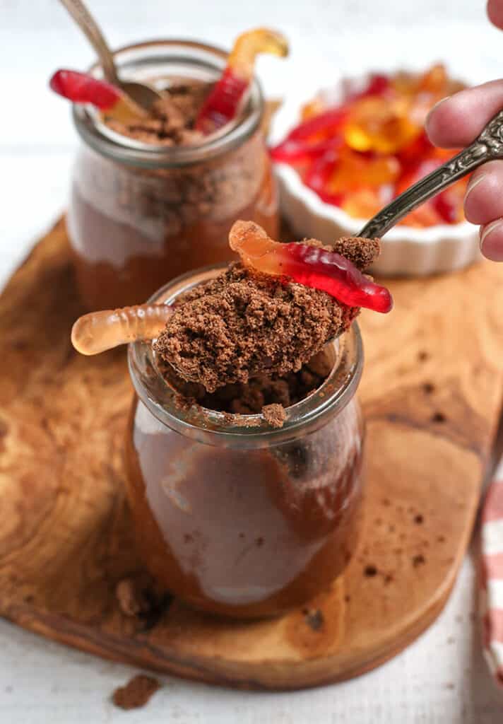 vegan chocolate dirt pudding cups with a spoon taking a bite