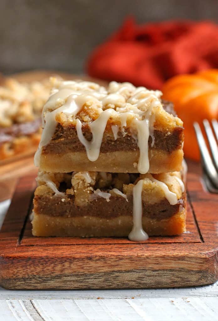 stack of paleo pumpkin crumb bars with glaze dripping down the side