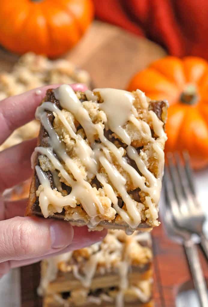 hand holding a paleo vegan pumpkin pie crumb bar with the top showing the crumb and glaze 