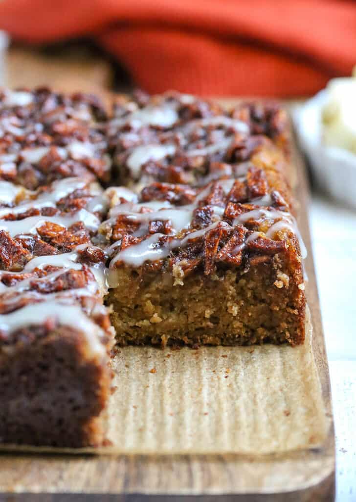 olive oil apple cake on a cutting board with a piece missing