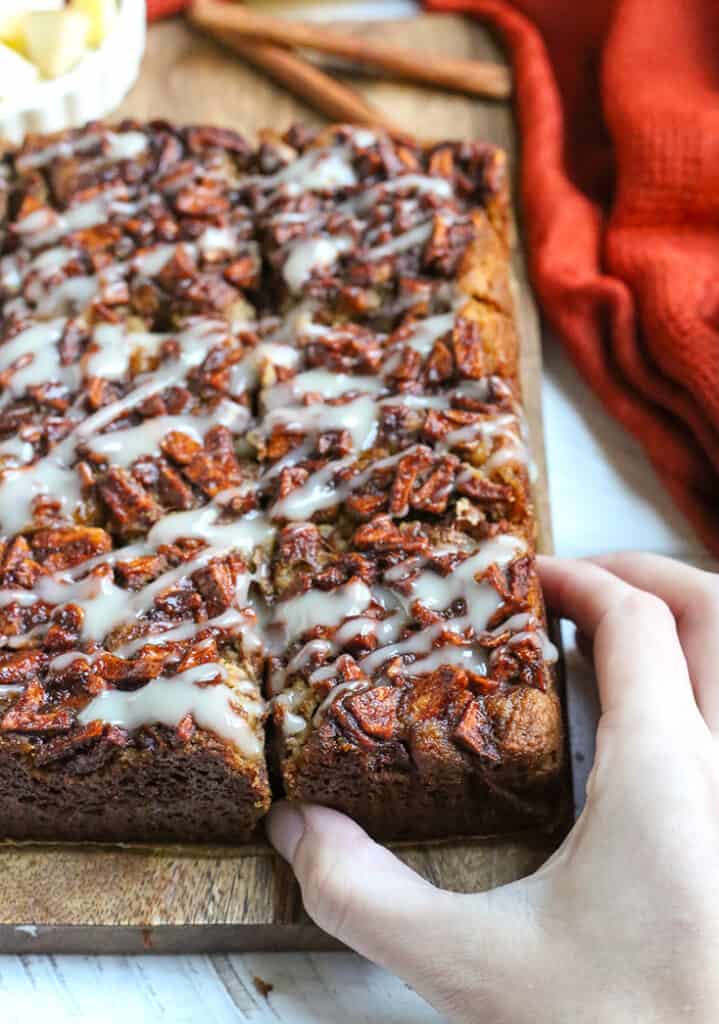 hand reaching for a piece of olive oil apple cake