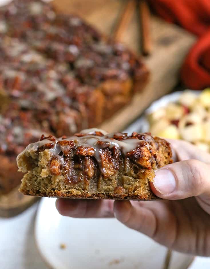 hand holding a piece of paleo olive oil apple cake with a bite taken