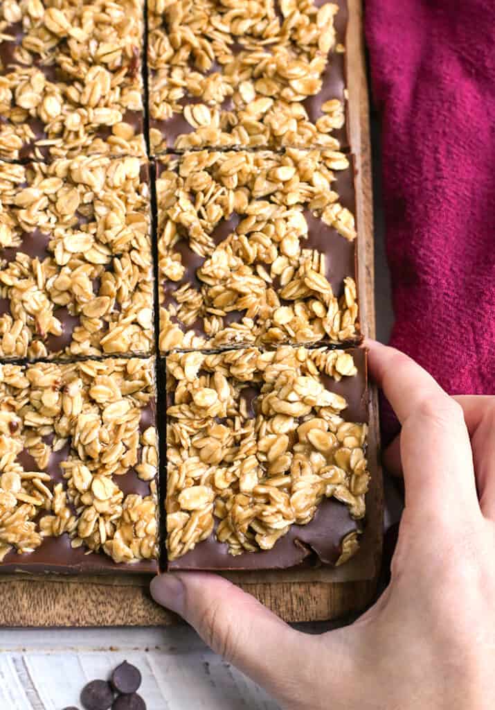 a hand reaching for a gluten free oatmeal chocolate fudge bar