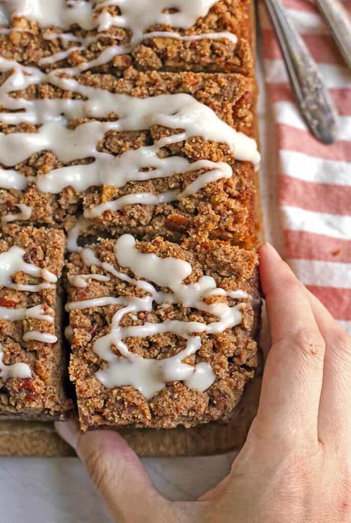 a hand reaching for a piece of paleo coffee cake, view from the top 