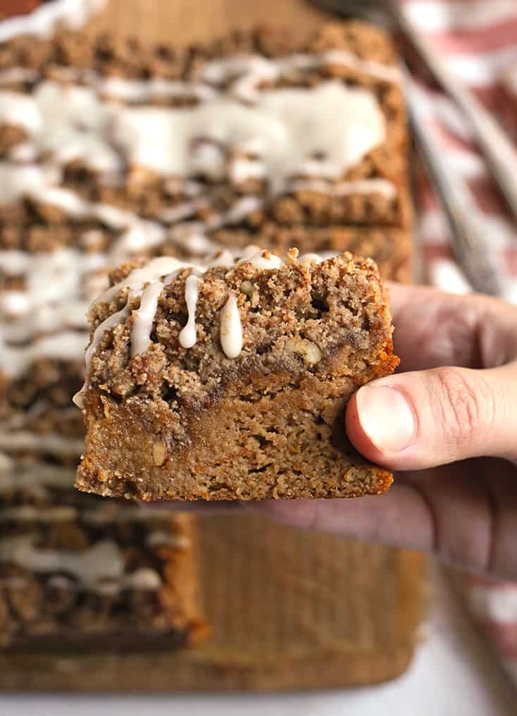 a hand holding a piece of paleo sweet potato pecan coffee cake showing the crumb topping 