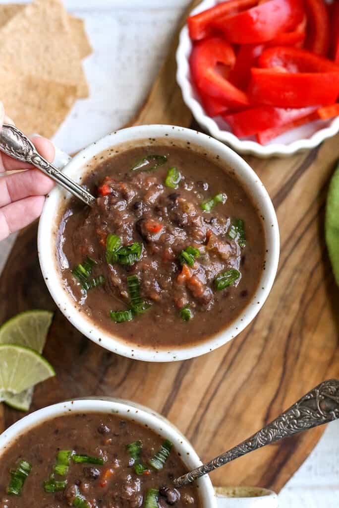 black bean soup in a bowl with a spoon taking a bite 