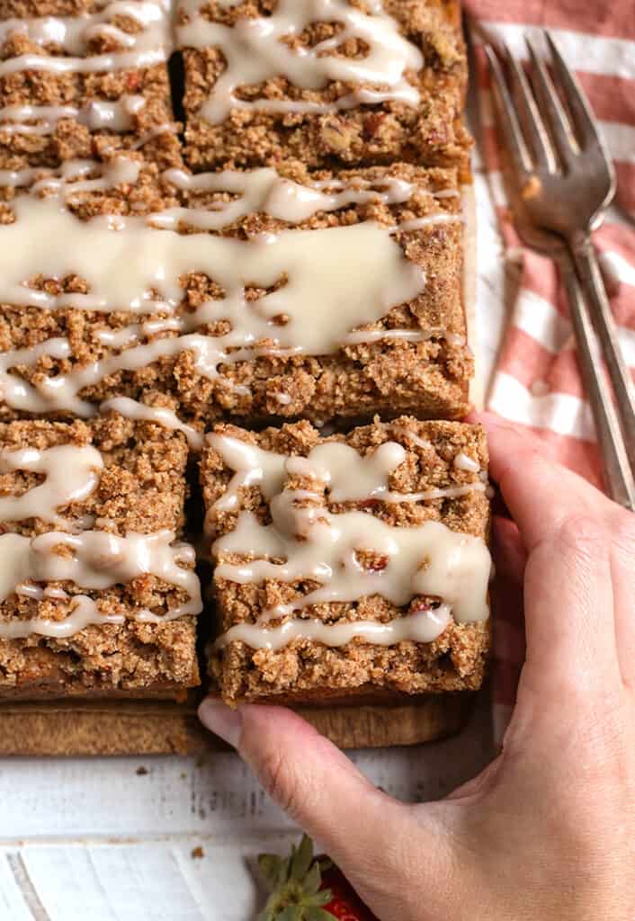 hand grabbing a piece of paleo coffee cake, top view 