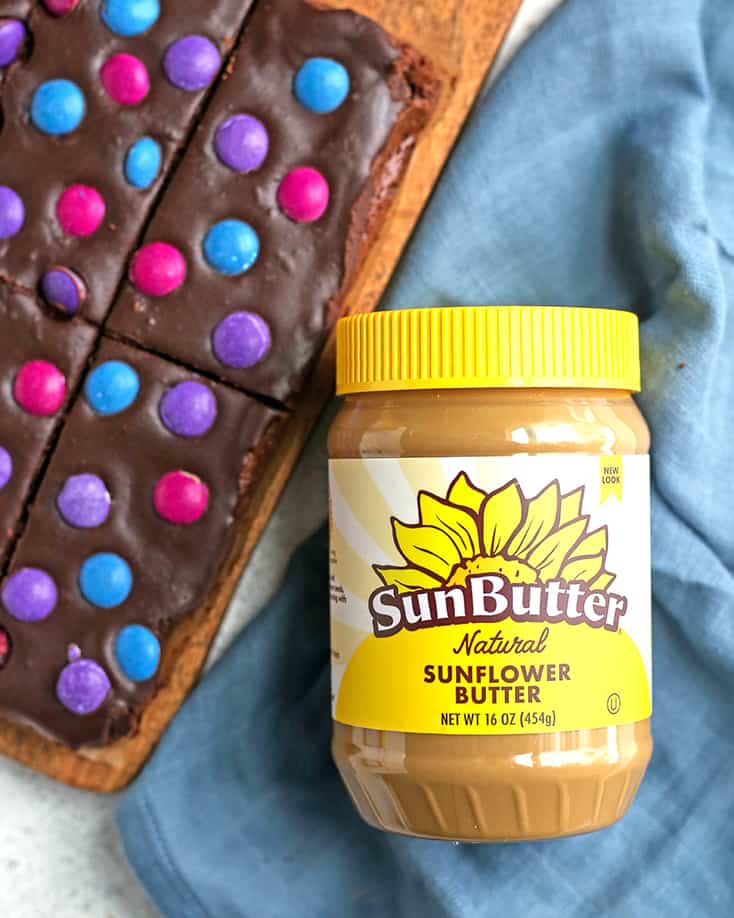 a jar of sunbutter with a plate of cosmic brownies 