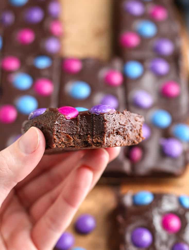 hand holding a vegan brownie with a bite taken out of it 