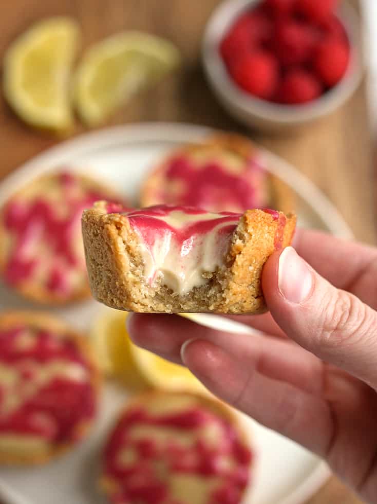 hand holding a paleo lemon cheesecake cup with a bite taken out 