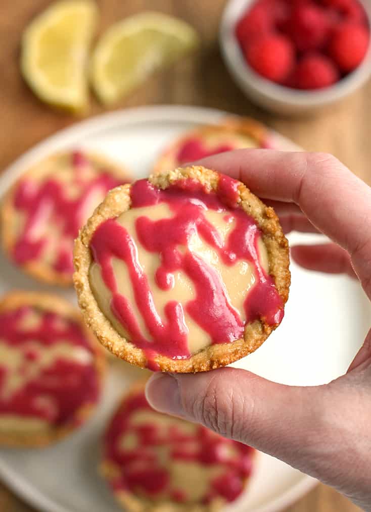 a hand holding a paleo cheesecake cup with the raspberry topping showing 
