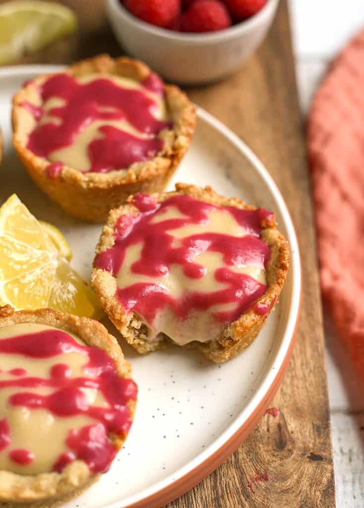 vegan lemon cheesecake cookie cups on a plate with a bite taken out of one 