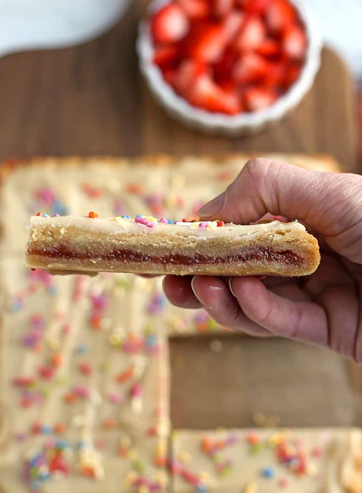 a hand holding a vegan strawberry pop tart showing the layers