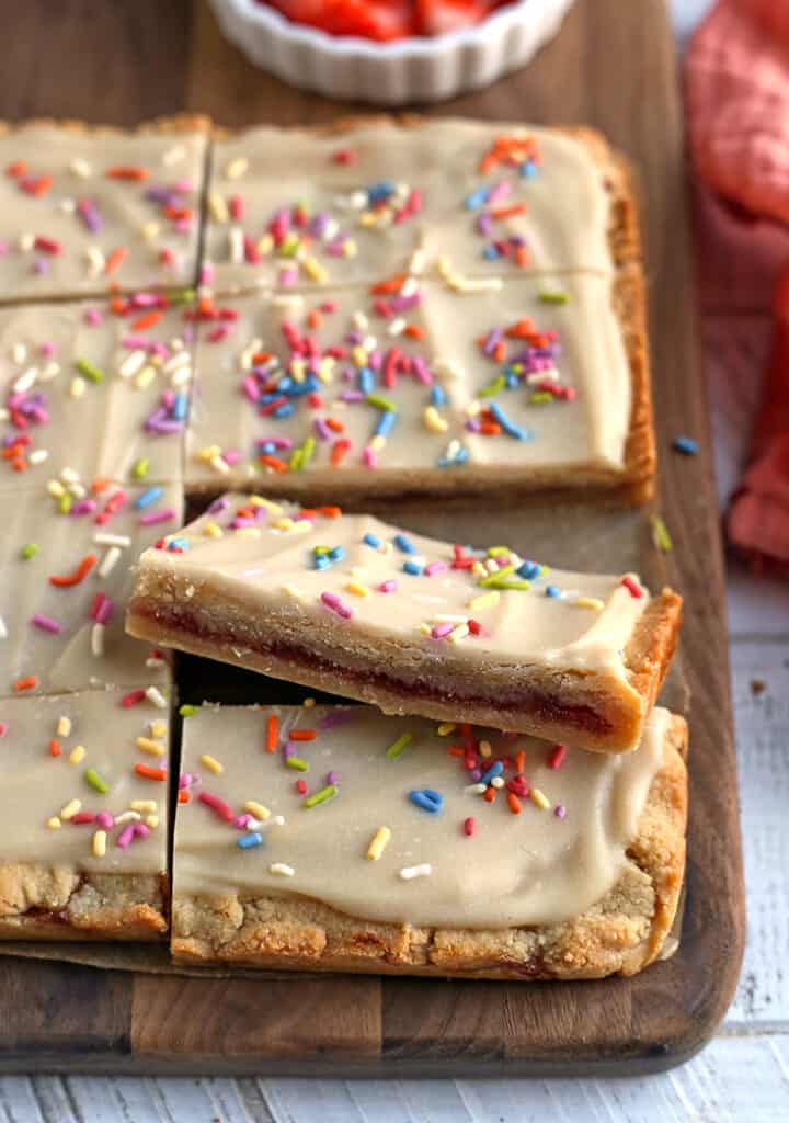 strawberry pop tart bars on a cutting board with the middle filling showing 