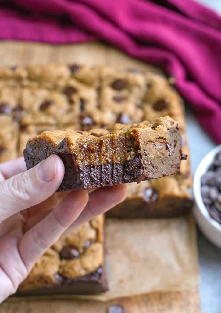 a hand holding a paleo cookie brownie with a bite taken out of it 