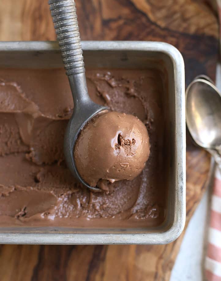 an ice cream scoop scooping chocolate ice cream from a pan
