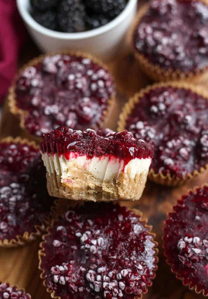 up close shot of blackberry cheesecake with a bite taken out of it showing the layer 