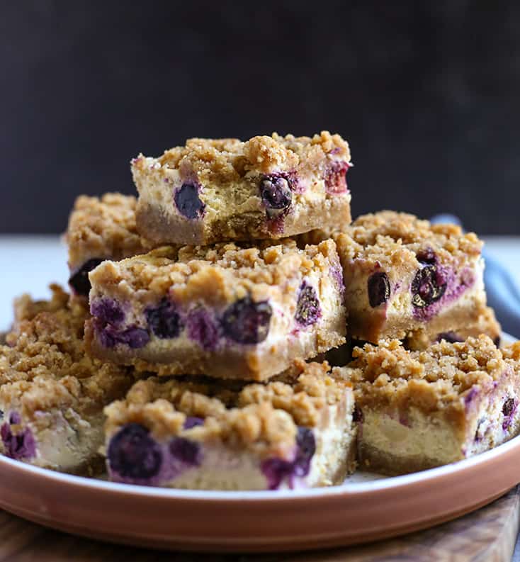 stack of gluten free blueberry cheesecake bars with a bite taken out of the top one
