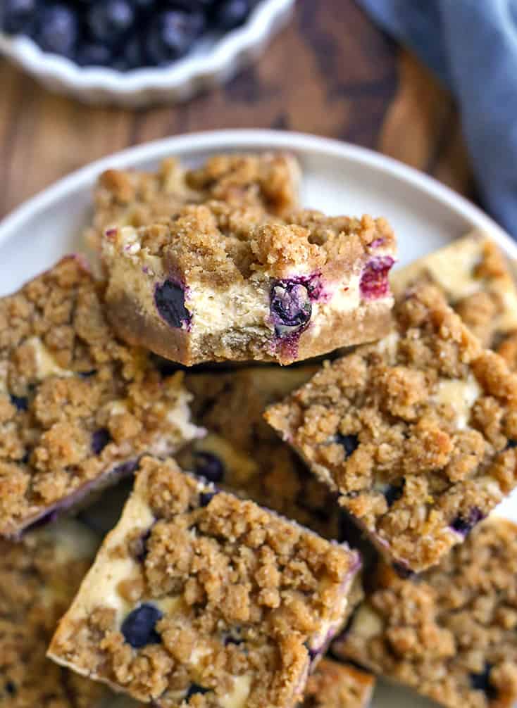 plate of gluten free blueberry cheesecake slices with a bite taken out of one 