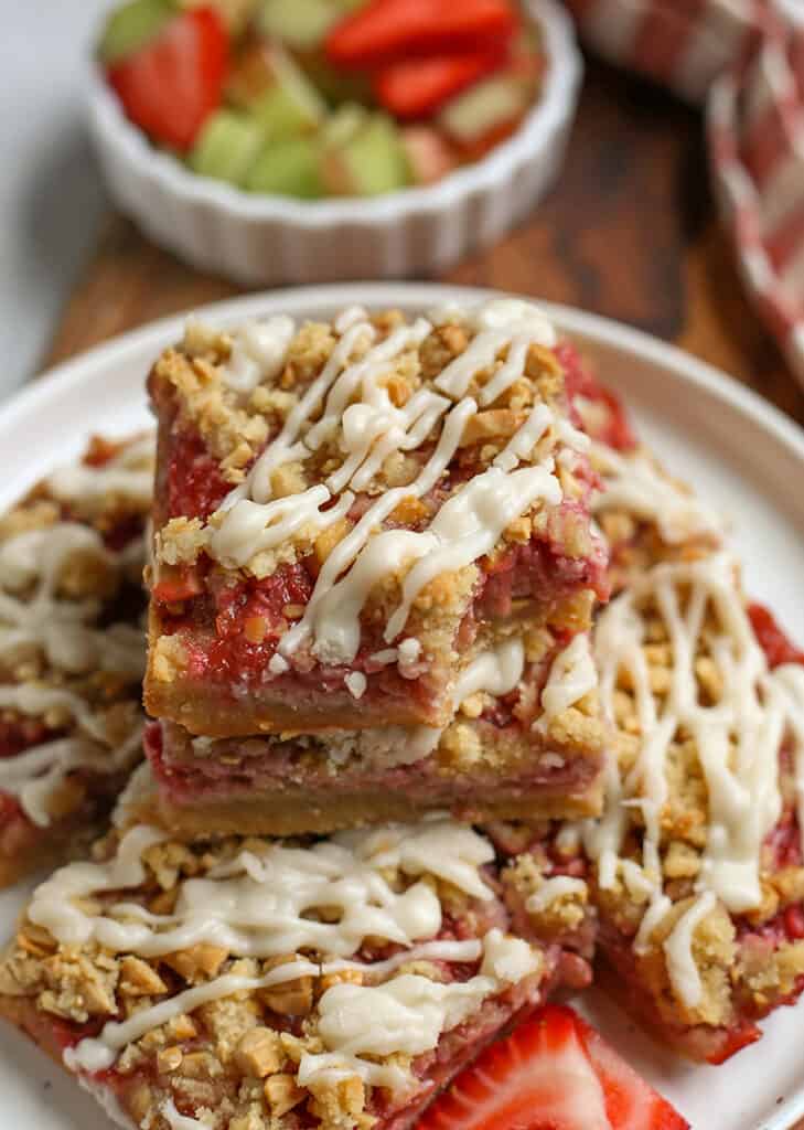 vegan strawberry rhubarb bars on a plate with a bite taken out of the top one 